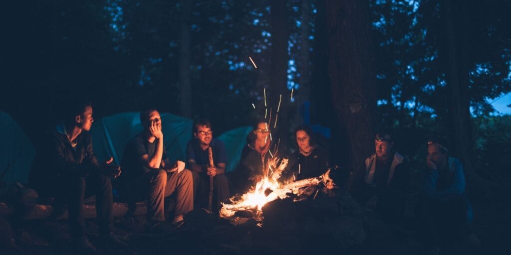 Group Bonfire Night during a family camping escape, featuring warm firelight, music, storytelling, and outdoor fun in a scenic setting.