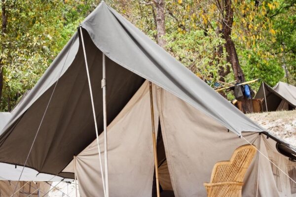 Riverside camping setup in Rishikesh with luxury tents, bonfire, and scenic mountain backdrop offering adventure activities and nature experiences.