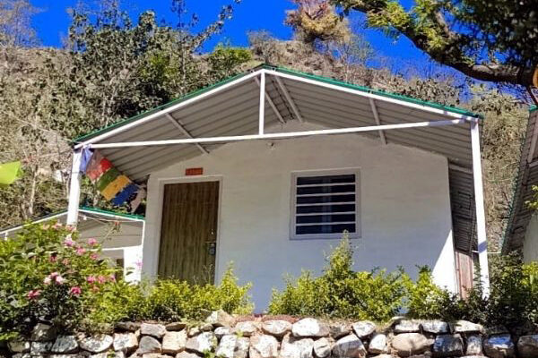 Riverside camping setup in Rishikesh with luxury tents, bonfire, and scenic mountain backdrop offering adventure activities and nature experiences.