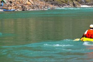 Tourist enjoying a kayaking adventure on calm blue waters surrounded by scenic landscapes and nature.