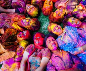 Tourists enjoying a colorful Holi party with riverside camping in Rishikesh, featuring bonfire, music, and adventure activities in a scenic Himalayan setting.